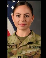 CPT Hicks in her OCP uniform in front of a flag