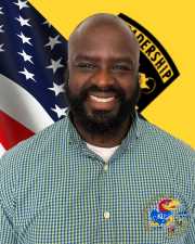 Mr. Hoskins standing in front of the American flag and Cadet Command Flag