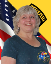 Mrs. Persinger standing in front of the American flag and Cadet Command Flag